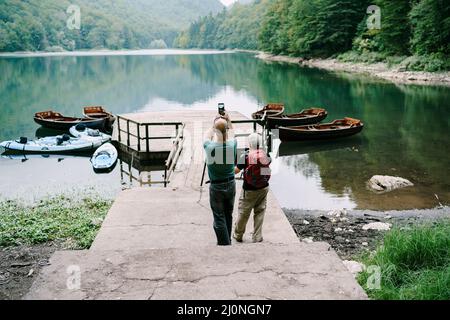 Mann und Frau fotografieren Boote am Pier am Lago di Prags. Italien Stockfoto