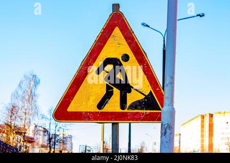 Das leuchtend orange Warnschild Road under Construction in der Nähe der Asphaltreparaturzone in der Stadt. Stockfoto