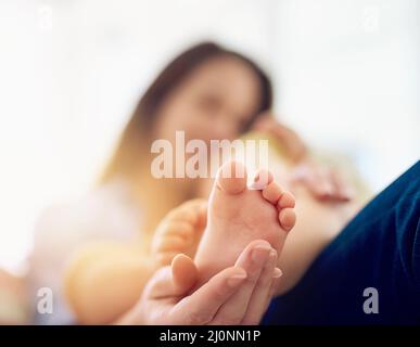 Genießen Sie die kleinen Dinge. Eine kurze Aufnahme einer Mutter, die den Fuß ihres Babys berührt. Stockfoto
