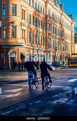 Silhouette eines jungen Paares von Radfahrern auf Fahrrädern, die darauf warten, dass sich das Licht an einer Kreuzung ändert Stockfoto