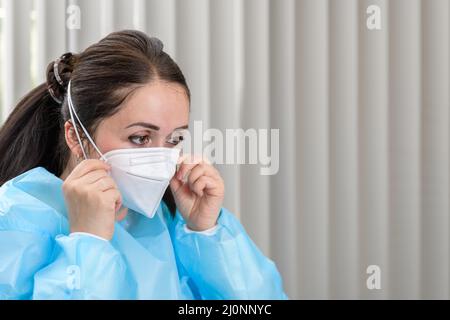 Arzt, der die Covid-19 N95-Maske in der Aufnahmestelle vor dem Besuch des Patienten anpasst Stockfoto