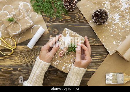 Draufsicht Hände halten weihnachtsgeschenk mit Pflanzen Kiefernzapfen. Hohe Qualität und Auflösung schönes Fotokonzept Stockfoto