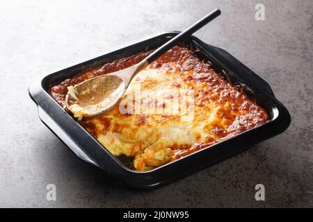 Portugiesischer Auflauf Bacalhau espiritual köstlicher Kabeljau, der mit Zwiebeln gekocht wird, geriebene Karotten, die mit geriebenem Käse in der Backform in der Nähe bestreut werden. Hori Stockfoto