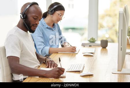 Ja, ich nehme Ihre Anforderungen zur Kenntnis. Aufnahme von zwei Callcenter-Mitarbeitern zusammen. Stockfoto
