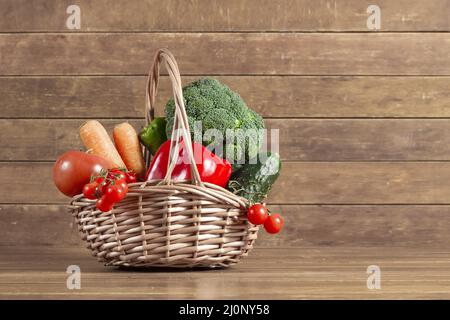 Holzhintergrund mit Korb voller Gemüse. Hohe Qualität und Auflösung schönes Fotokonzept Stockfoto