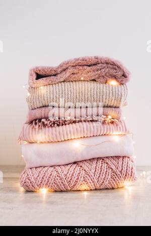 Stapel Strickpullover mit Girlande auf dem Boden. Hohe Qualität und Auflösung schönes Fotokonzept Stockfoto