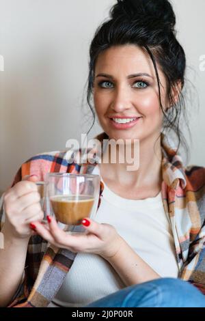 Blauäugige Frau mittleren Alters, die mit einer Tasse Kaffee sitzt Stockfoto