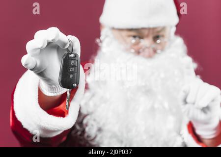 Santa claus hält den Autoschlüssel in der Hand. Hohe Qualität und Auflösung schönes Fotokonzept Stockfoto