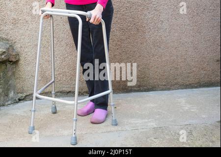Alte Person mit Gehrahmen im Haus Stockfoto