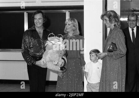 Diana, Prinzessin von Wales beim Konzert von Neil Diamond im National Exhibition Centre, Birmingham. Die Prinzessin, fast 7 Monate schwanger, wird im Chat mit dem Sänger, seiner Frau Marcia und dem Sohn Micha dargestellt. Das kuschelige „Garfield“-Spielzeug wird für Prinz William von Micha überreicht. 5.. Juli 1984. Stockfoto