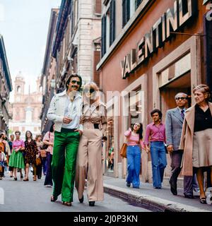 Vintage Rome 1970s, stilvolles Paar beim Spaziergang durch das Modegeschäft Valentino, die Einkaufsstraße Via dei Condotti, Italien, Europa, Stockfoto