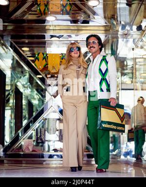 Vintage Rome 1970s, stilvolles Paar, das vom Modegeschäft Valentino Uomo, der Einkaufsstraße Via dei Condotti, Italien, Europa, Stockfoto