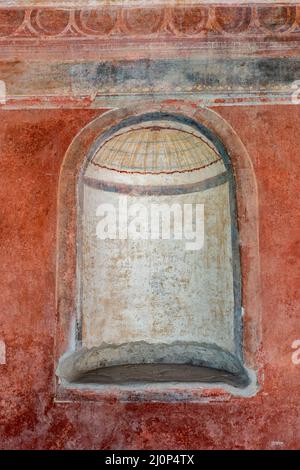 Gewölbte Nische in rot gemalten Wand im Haus von Julia Felix (Praedia di Giulia Felice) in der antiken Stadt Pompeji in Pompei, Italien. Stockfoto