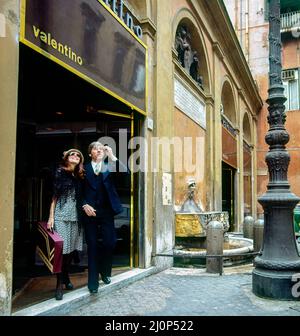 Vintage Rome 1970s, stilvolles Paar mittleren Alters, das aus dem Modegeschäft Valentino, der Einkaufsstraße Via dei Condotti, Italien, Europa, Stockfoto