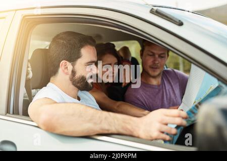 Alle Systeme gehen. Aufnahme einer Gruppe junger Freunde, die sich bereit machen, mit ihrem Fahrzeug zu ihrem Ziel zu fahren, während sie sich eine Karte ansehen. Stockfoto