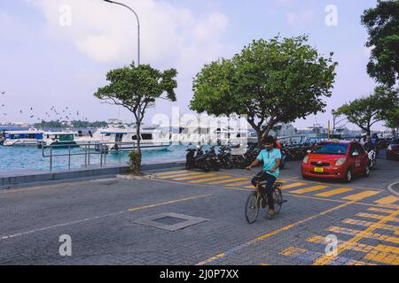 Maledivische Einheimische fahren auf den Bikes auf den Straßen von Male City Stockfoto