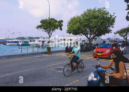 Maledivische Einheimische fahren auf den Bikes auf den Straßen von Male City Stockfoto