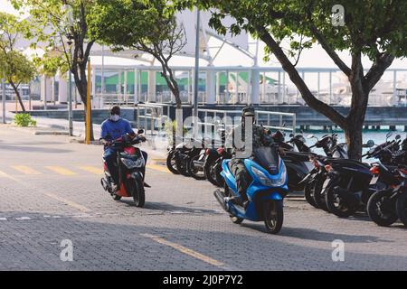 Maledivische Einheimische fahren auf den Bikes auf den Straßen von Male City Stockfoto