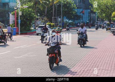 Maledivische Einheimische fahren auf den Bikes auf den Straßen von Male City Stockfoto