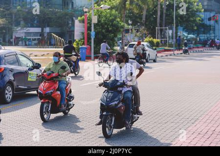 Maledivische Einheimische fahren auf den Bikes auf den Straßen von Male City Stockfoto