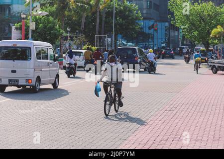 Maledivische Einheimische fahren auf den Bikes auf den Straßen von Male City Stockfoto