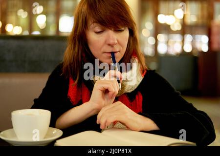 Frau im Café schreibt in Tagebuch, Bullet Journal. Langsames Leben, soziale Entgiftung, freiberuflich, Planung Stockfoto