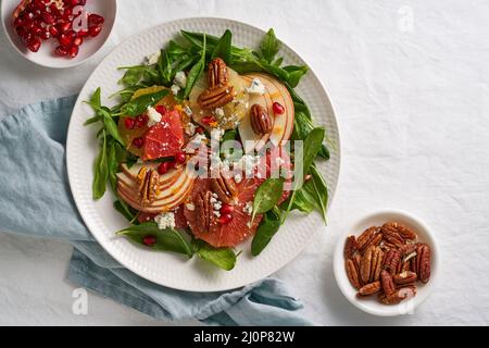 Früchte Zitrussalat mit Nüssen, grünen Salatblättern. Spinat mit Orange, Grapefruit, Äpfeln, Pecan Stockfoto