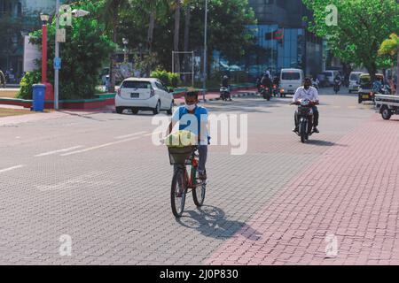 Maledivische Einheimische fahren auf den Bikes auf den Straßen von Male City Stockfoto