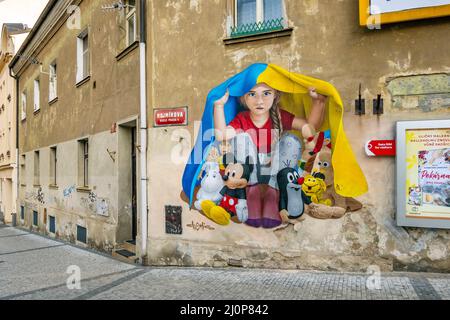 Ein Mädchen, das unter ukrainischer Flagge Schutz nimmt, Wandgemälde von ChemiS (tschechischer Künstler mit kasachischen Wurzeln, Dmitri Proshkin), Nusle, Prag, Tschechische republik Stockfoto