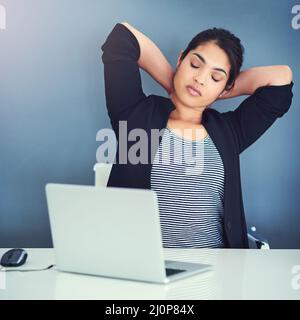 Alles, was ich jetzt brauche, ist eine Pause. Eine kurze Aufnahme einer schönen jungen Geschäftsfrau in ihrem Büro. Stockfoto