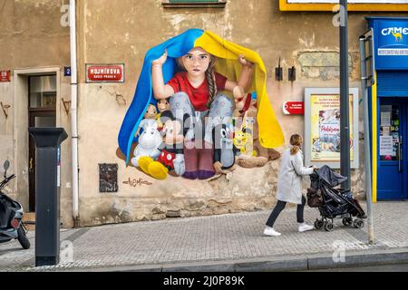 Ein Mädchen, das unter ukrainischer Flagge Schutz nimmt, Wandgemälde von ChemiS (tschechischer Künstler mit kasachischen Wurzeln, Dmitri Proshkin), Nusle, Prag, Tschechische republik Stockfoto