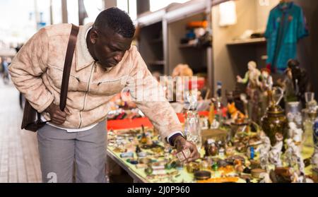 Afroamerikanischer Mann wählt Antiquitäten auf dem Flohmarkt Stockfoto