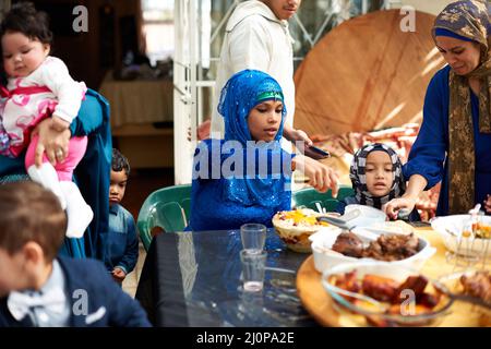 Essen bringt alle zusammen. Aufnahme einer muslimischen Familie, die zusammen isst. Stockfoto