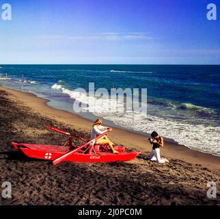 Vintage Italy 1970s, Fotografin fotografiert, Modelemodell weiblich, rotes Ruderrettungsboot, Strand Kursaal, Lido di Ostia, Latium, Europa, Stockfoto