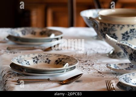 Porzellangeschirr. Tischservice auf dem Tisch eingestellt. Alte Teller und Löffel. Ein elegant eingerichteter Tisch. Stockfoto