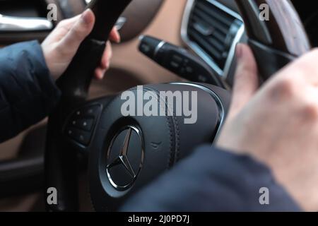 Charkov, Ukraine - 14. März 2022: Mercedes Benz Lenkrad und Frauenhand. Armaturenbrett und Innenansicht Stockfoto