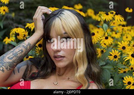 Ein schönes Brünette Model posiert in Einem Feld von gelben Blumen, während es das Sommerwetter genießt Stockfoto