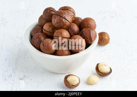 Platte mit Mandeln in Endokarp, ganzen und gehackten offenen Nüssen Stockfoto