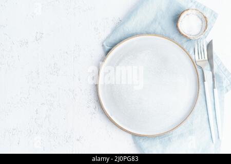 Leere weiße Keramikplatte, Gabel und Messer auf weißem Steintisch reinigen, Kopierraum, Stockfoto