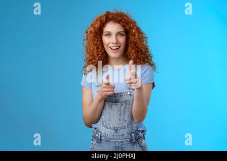 Gotcha. Coole freche gut aussehende Rothaarige lockige Frau zeigt Kamera Finger Pistolen freche Einführung lächelnd aufgeregt mit Fu Stockfoto