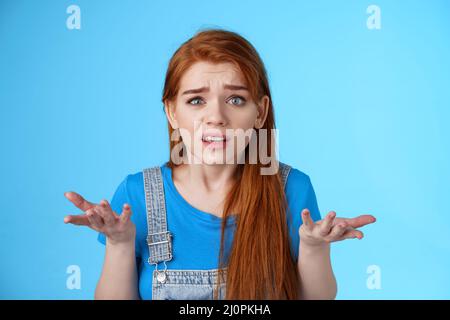 Verwirrt verwirrt Rotschopf nette Frau in den Hinterhalt schauen, heben die Hände zuckend unsicher, runzelig verwirrt, kann nicht verstehen, was h Stockfoto