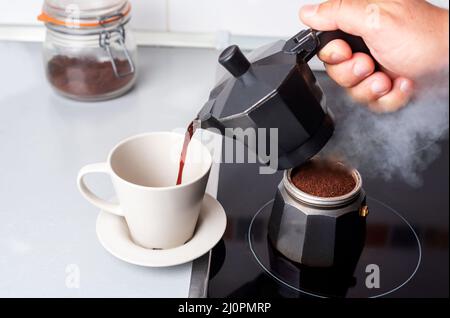 Zerlegte Kaffeemaschine mit einem Teil am Feuer und dem anderen, der Kaffee in einer Tasse serviert. Stockfoto