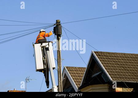 Pontyclun, Wales - 2022. märz: BT-Telefoningenieur in einer hydraulischen Plattform für Kirschpflücker, die Drähte an einem Telegrafenmast repariert. Stockfoto