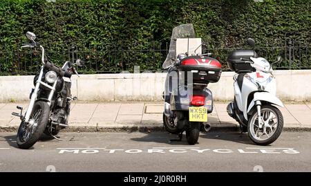 London, England - 2021. August: Reihe von Motorrädern und Motorrollern, die in einem eigenen Parkplatz auf einer Straße im Zentrum von London geparkt sind Stockfoto