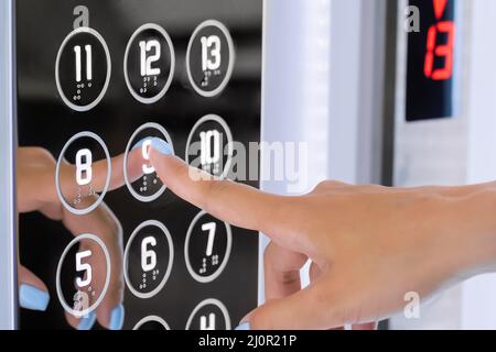 Frau drückt den Fahrstuhlknopf im neunten Stock mit dem Finger - Nahaufnahme Stockfoto