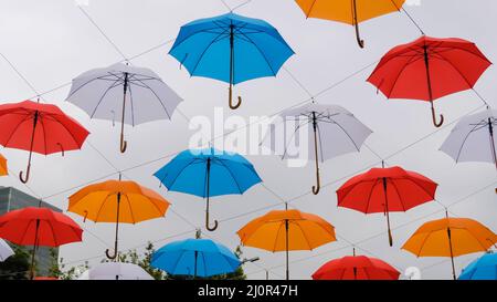 Bunte Regenschirme hängen beim Outdoor-Festival am bewölkten Himmel Stockfoto