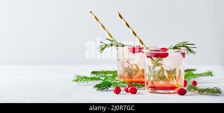 Alkoholischer Cocktail oder alkoholfreier Mocktail mit Wodka und vereisten Preiselbeeren mit Tannenzweigen zu weihnachten Stockfoto