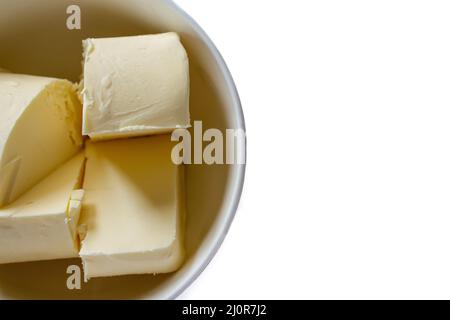 Butterstücke in Schüssel, isoliert auf weißem Hintergrund. Draufsicht auf Bio-Butter. Stockfoto