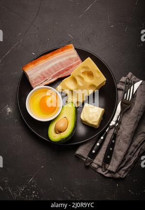 Lebensmittel für die Keto-Diät auf schwarzem Teller auf dunklem Hintergrund Stockfoto