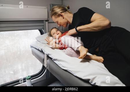 Vater mit Kind travalling in den Zug, Spaß zu genießen Szene durch Fenster, während auf der Eisenbahn zusammen im Schlafwagen fahren Stockfoto